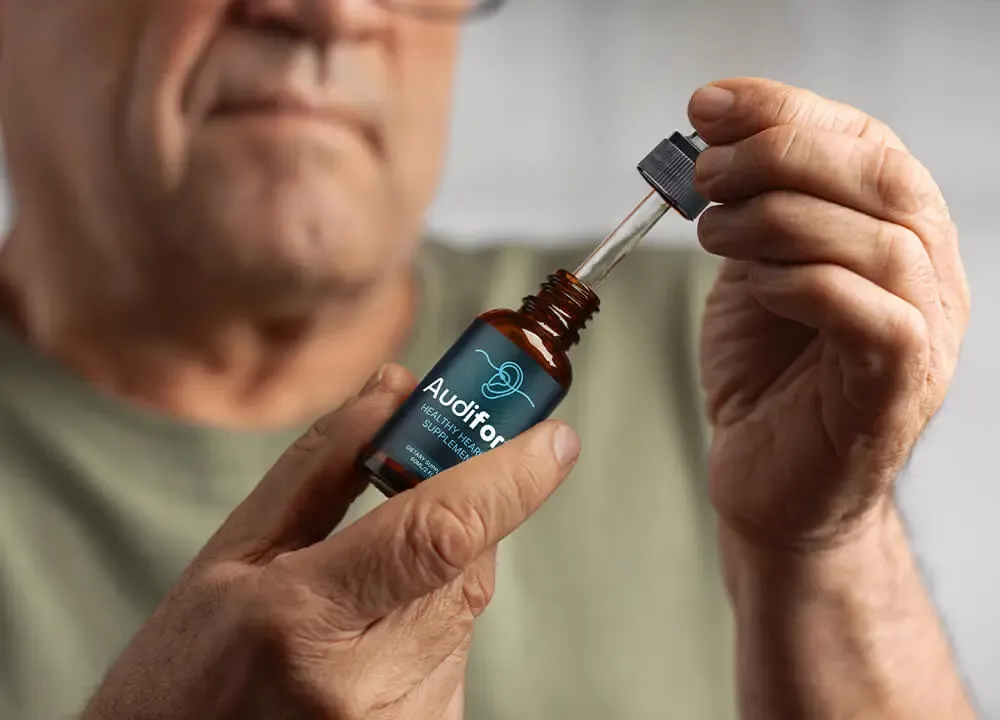 Close-up of a person holding an eye dropper with Audifort liquid formula to showcase daily serving directions.
